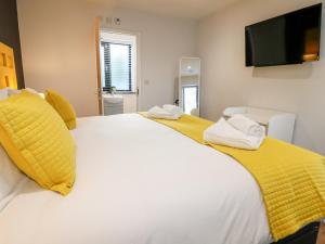 um quarto com uma grande cama branca com almofadas amarelas em The Coach House, Bank Top Farm em Ashbourne