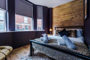 a bedroom with a bed with a wooden headboard and windows at Four Bedroom Urban Home hosted by MCR Dens in Manchester
