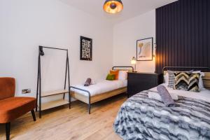 a bedroom with two beds and a chair in it at Four Bedroom Urban Home hosted by MCR Dens in Manchester