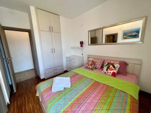 a bedroom with a bed with a colorful blanket and a mirror at Apartment Maestral with sea view in Pržno