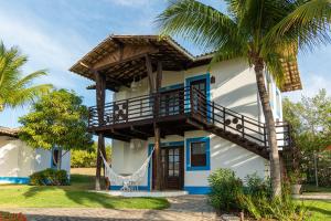 a house with a balcony and palm trees at Hotel Tibau Lagoa in Pipa