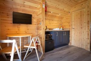 a kitchen with a table and a tv on a wooden wall at Kings Caves Glamping in Torbeg