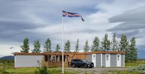 a truck parked in front of a house with a flag at Adventure Eagle Cottege in Geysir