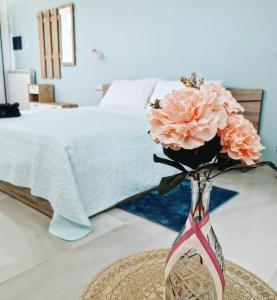 un jarrón con flores rosas en una mesa junto a una cama en La Suite della casa bianca, en San Salvatore Telesino