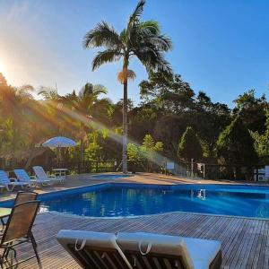 a swimming pool with chairs and a palm tree at Fazenda dos Caetés in Camboriú