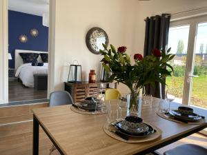 une salle à manger avec une table et un vase de fleurs dans l'établissement *** Domaine des Noyers - Proche centre Ville, à Châteauneuf-sur-Loire