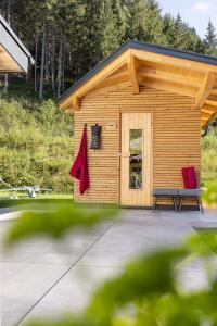 a shed with two red chairs in front of it at Fichtenlodge Stubaital in Neustift im Stubaital