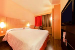 a bedroom with a large white bed and a red window at Ibis Sertaozinho in Sertãozinho