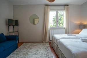um quarto com 2 camas, um sofá azul e um espelho. em Le Mas de Sevrier em Sévrier