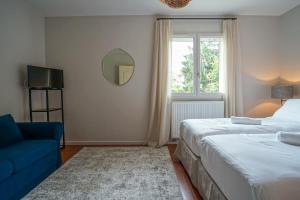 a bedroom with two beds and a blue couch and a mirror at Le Mas de Sevrier in Sévrier