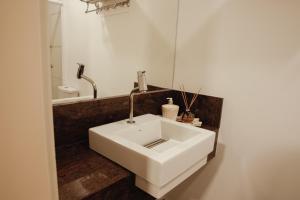 La salle de bains est pourvue d'un lavabo blanc et d'un miroir. dans l'établissement Rodeio Hotel, à Rodeio Bonito