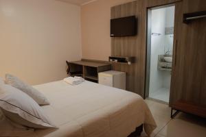 a bedroom with a bed and a bathroom with a sink at Rodeio Hotel in Rodeio Bonito