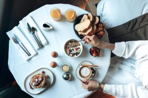 una persona seduta a un tavolo bianco con prodotti per la colazione di Domaine Des Hautes Fagnes a Ovifat