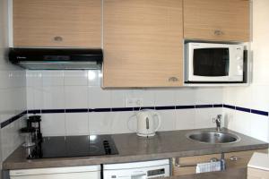 una pequeña cocina con fregadero y microondas en L'Aigue-Marine emplacement parfait, parking privé, en Arzon