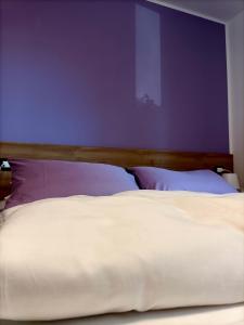 a bedroom with a white bed with a purple wall at B&B Rio Rai in Gemona del Friuli