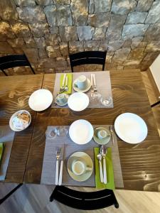 a wooden table with white plates and silverware on it at B&B Rio Rai in Gemona del Friuli