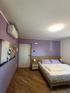 1 dormitorio con cama y pared púrpura en B&B Rio Rai, en Gemona del Friuli