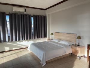 a bedroom with a large white bed and windows at Kirin Guesthouse and Restaurant in Port Louis