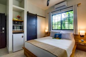 1 dormitorio con 1 cama grande y ventana en The Sea Glass Inn, en Placencia Village