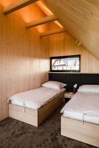 two beds in a room with wooden walls at Czarne Domki in Zwierzyniec