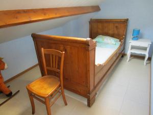 a wooden bed and a chair in a room at les palmiers in Vias