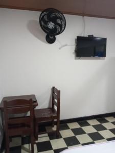 a room with a chair and a tv on a wall at Hospedaje Santa Bárbara in Buga
