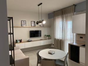 a living room with a white table and a tv at La Favola Apartment Orbassano in Orbassano