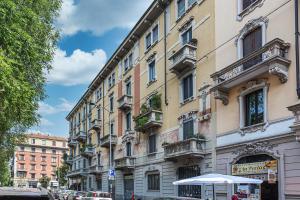duży budynek przy ulicy miejskiej z zaparkowanymi samochodami w obiekcie La Boutique Milano: appartamento in Porta Romana w Mediolanie