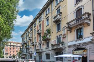 un grande edificio su una strada cittadina con auto parcheggiate di La Boutique Milano: appartamento in Porta Romana a Milano