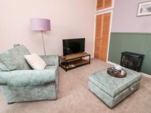 a living room with a couch and a chair and a tv at Islestone, 1 Temperance Terrace in Berwick-Upon-Tweed
