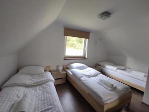 two beds in a room with a window at Domek u Hornika in Dursztyn