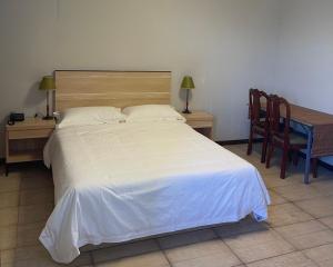 ein Schlafzimmer mit einem weißen Bett sowie einem Tisch und Stühlen in der Unterkunft Kirin Guesthouse and Restaurant in Port Louis