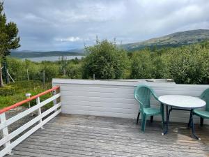 two chairs and a table on a wooden deck at Snøhetta Camping in Hjerkinn