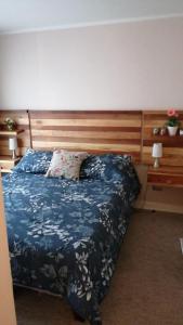 a bedroom with a bed with a wooden headboard at DEPARTAMENTOS TERMAS DE CHILLAN in Nevados de Chillan