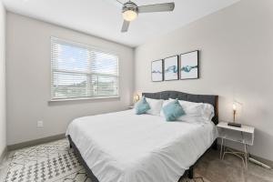 a white bedroom with a large bed with blue pillows at Modern & Chic 1BR Luxury Apts Close to Downtown & Airport in Austin
