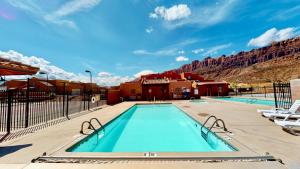 una piscina en un complejo con montañas en el fondo en Cairn House #4A7, en Moab