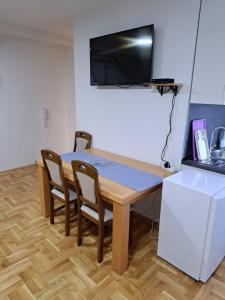 a dining room table with chairs and a television on the wall at Apartman Bubic 