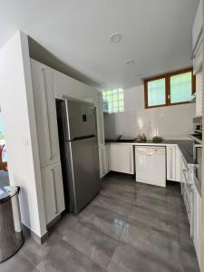 a kitchen with white cabinets and a stainless steel refrigerator at Maison spacieuse avec grand jardin et parking à 20min de Lyon in Simandres