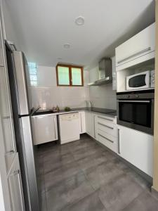 a large kitchen with white cabinets and appliances at Maison spacieuse avec grand jardin et parking à 20min de Lyon in Simandres