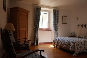 1 dormitorio con cama, ventana y silla en Lou Prat, en Meyrueis