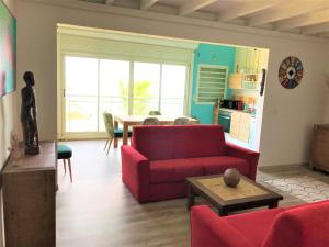 a living room with a red couch and a table at Crystal Beach, vue mer, accès direct plage et piscine, clim in Sèze