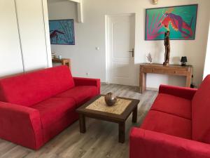 a living room with two red couches and a table at Crystal Beach, vue mer, accès direct plage et piscine, clim in Sèze