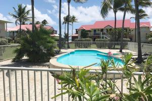a swimming pool with palm trees and houses at Crystal Beach, vue mer, accès direct plage et piscine, clim in Sèze