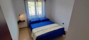 una piccola camera con letto blu e finestra di Grazioso e confortevole attico, costa sud-ovest a Gonnesa