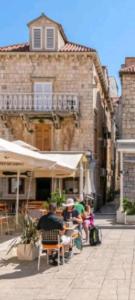 a group of people sitting at a table in front of a building at Vintage house al pozzo in Hvar