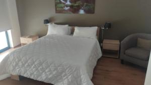 1 dormitorio con 1 cama blanca y 1 silla en Apartment 14, en St Paul's Bay
