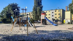 um parque infantil na areia em frente a um edifício em Casa del Mare, Apartments and more em Leba