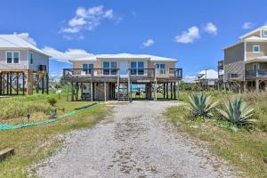 Lovely Dauphin Island Cottage with Deck and Gulf Views في دوفين آيلاند: منزل على الشاطئ مع طريق ترابي