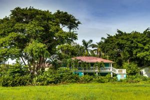 a house with a wrap around porch in a field at The Sea Glass Inn in Placencia Village