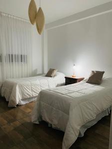 a bedroom with two beds and a table with a lamp at Garden 33 1A in Chivilcoy